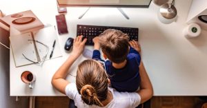 A working mom, with her child sitting on her lap.