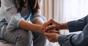 Friends hold hands during a conversation